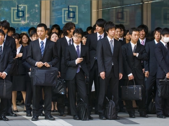 Tokyo , Japan – October 29, 2009: Japanese office workers stands outside an office building in Tokyo Japan financial district